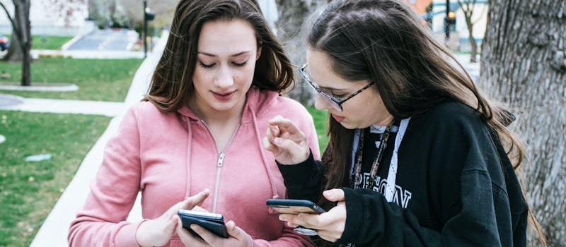 Duas jovens mulheres usam a app SNS 24 na rua